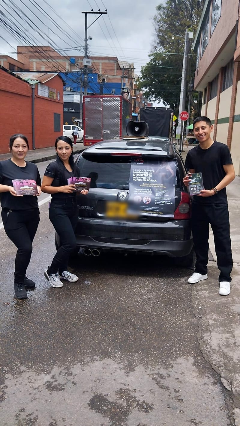 Equipo de Publimao con volantes de una gran inauguración junto al carro de perifoneo